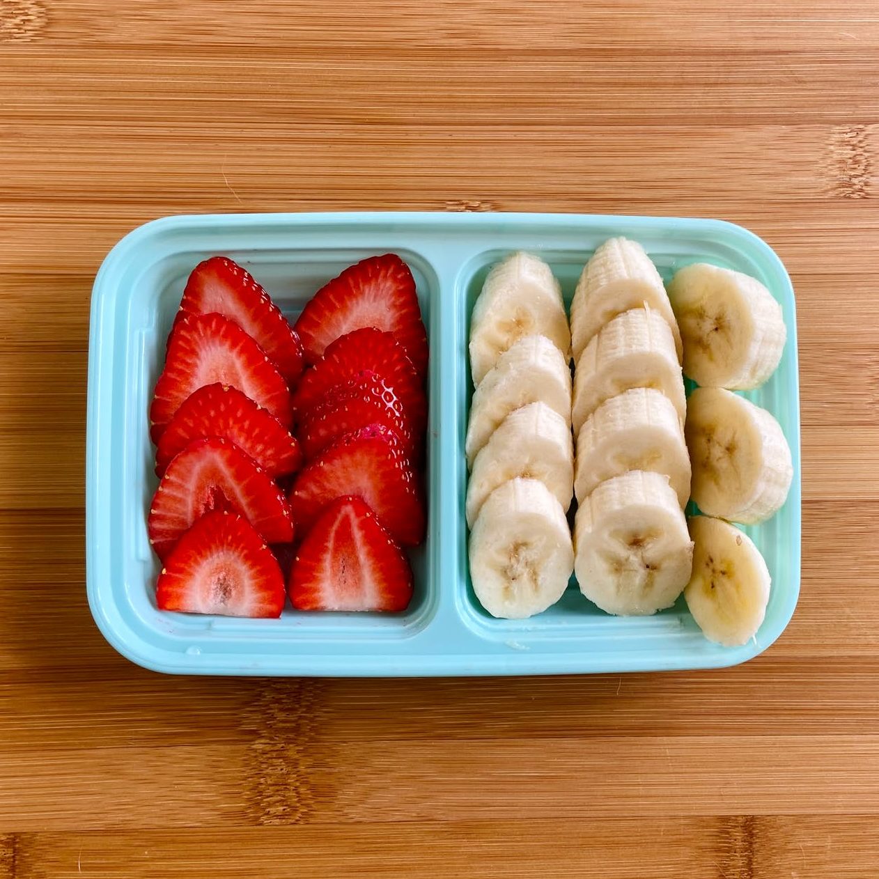 sliced strawberries and bananas on a plastic container